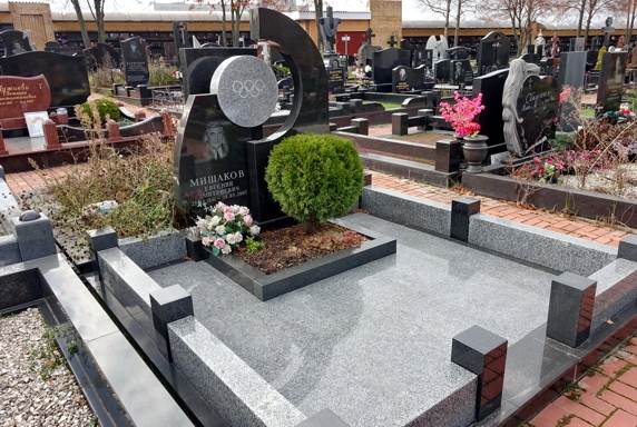 Сложный памятник с олимпийским символом и подстриженной туей